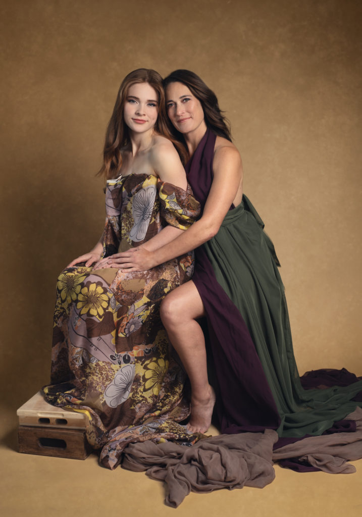A glamorous photo of a mother and daughter draped in silk fabric