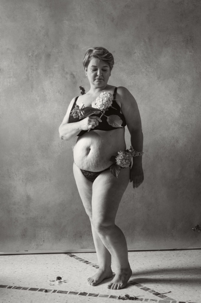 woman with stretch marks and flowers in a black and white photo showing body-positivity