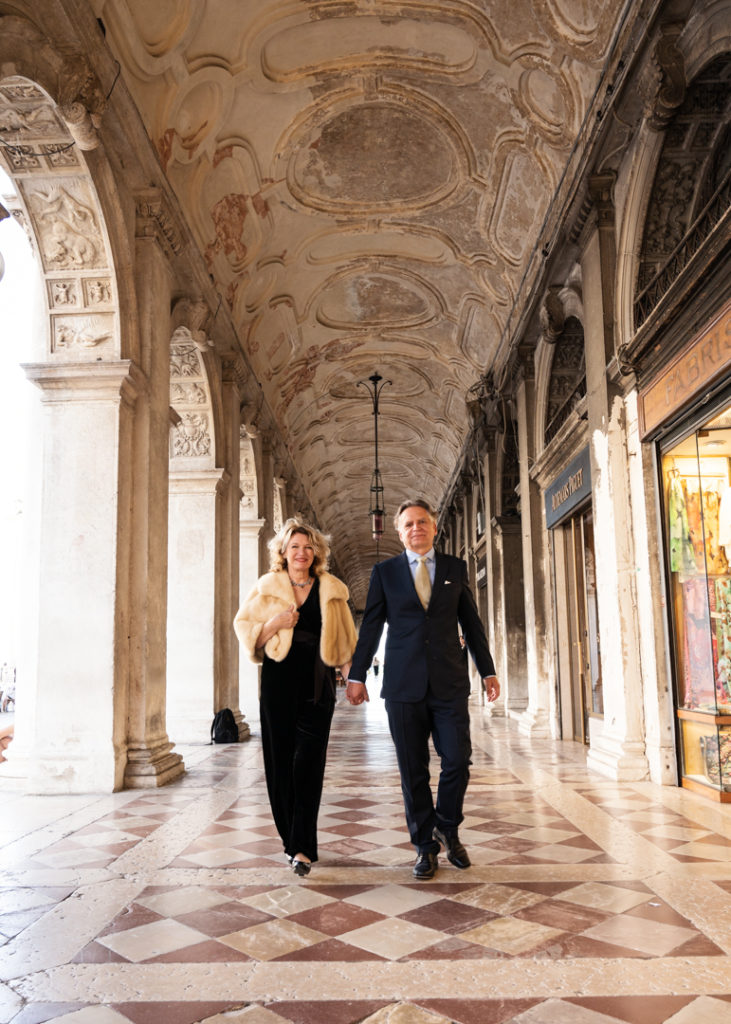 Newlywed couple walking under the archways near Caffè Florian, Venice