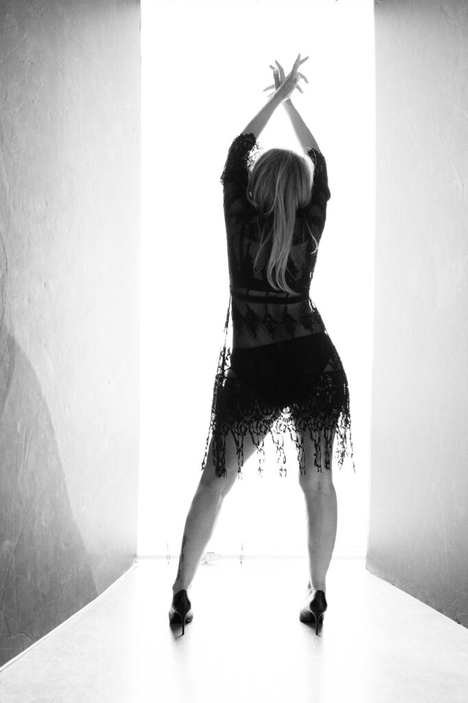 Black and white photo of a woman celebrating herself in black lace in a Real Client Experience