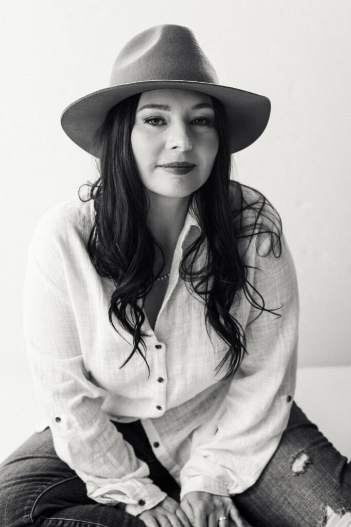 Black & White photo of a woman with a hat on and long dark hair for her body image journey photoshoot
